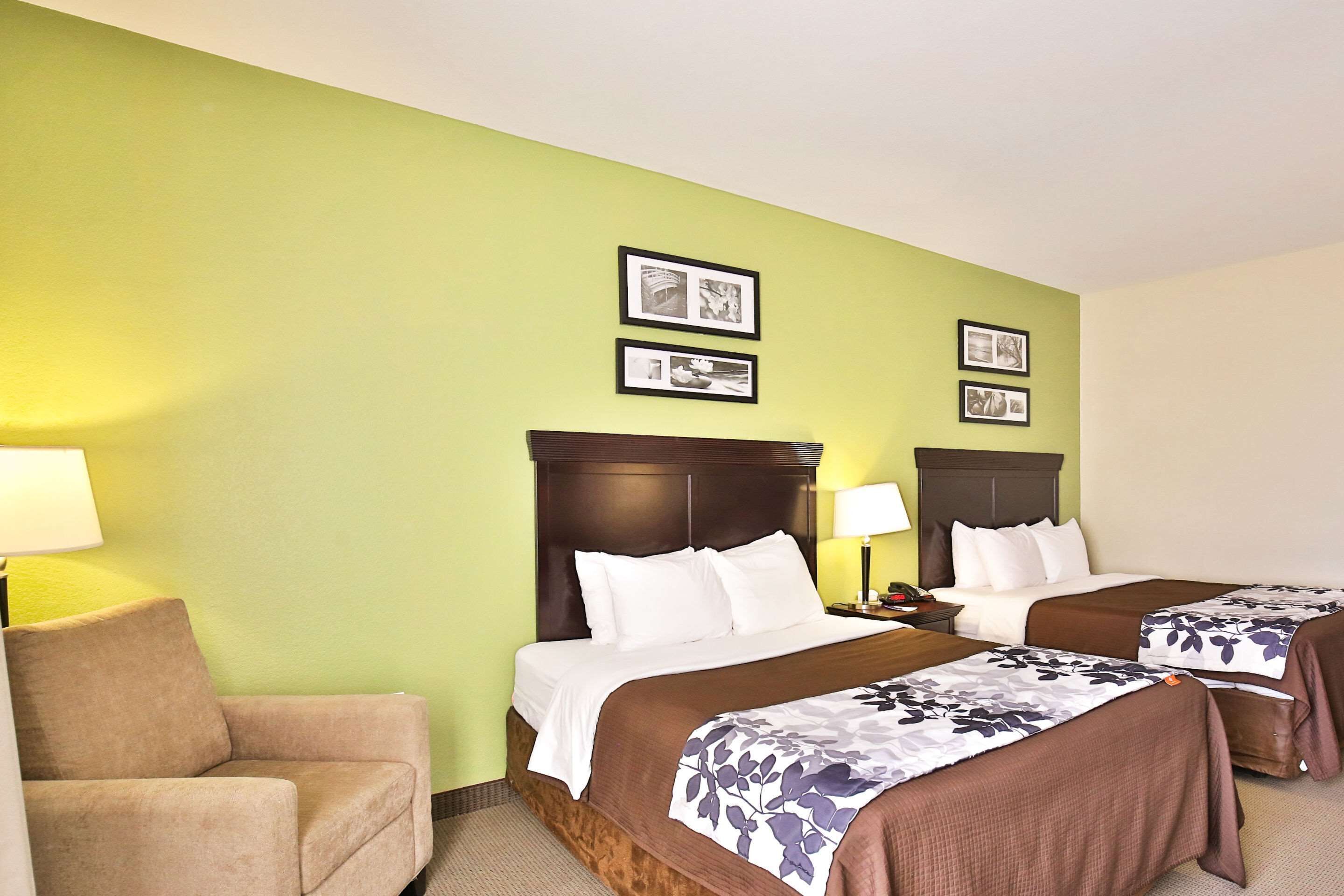 A hotel room with two beds, a sofa, and framed pictures on the wall.