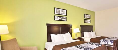 A hotel room with two beds, a sofa, and framed pictures on the wall.