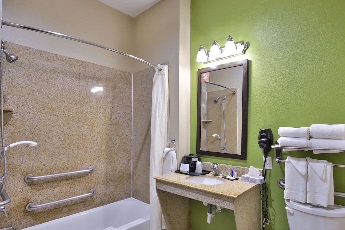 Une salle de bain équipée d’une douche, d’un lavabo, d’un miroir et d’un porte-serviettes.