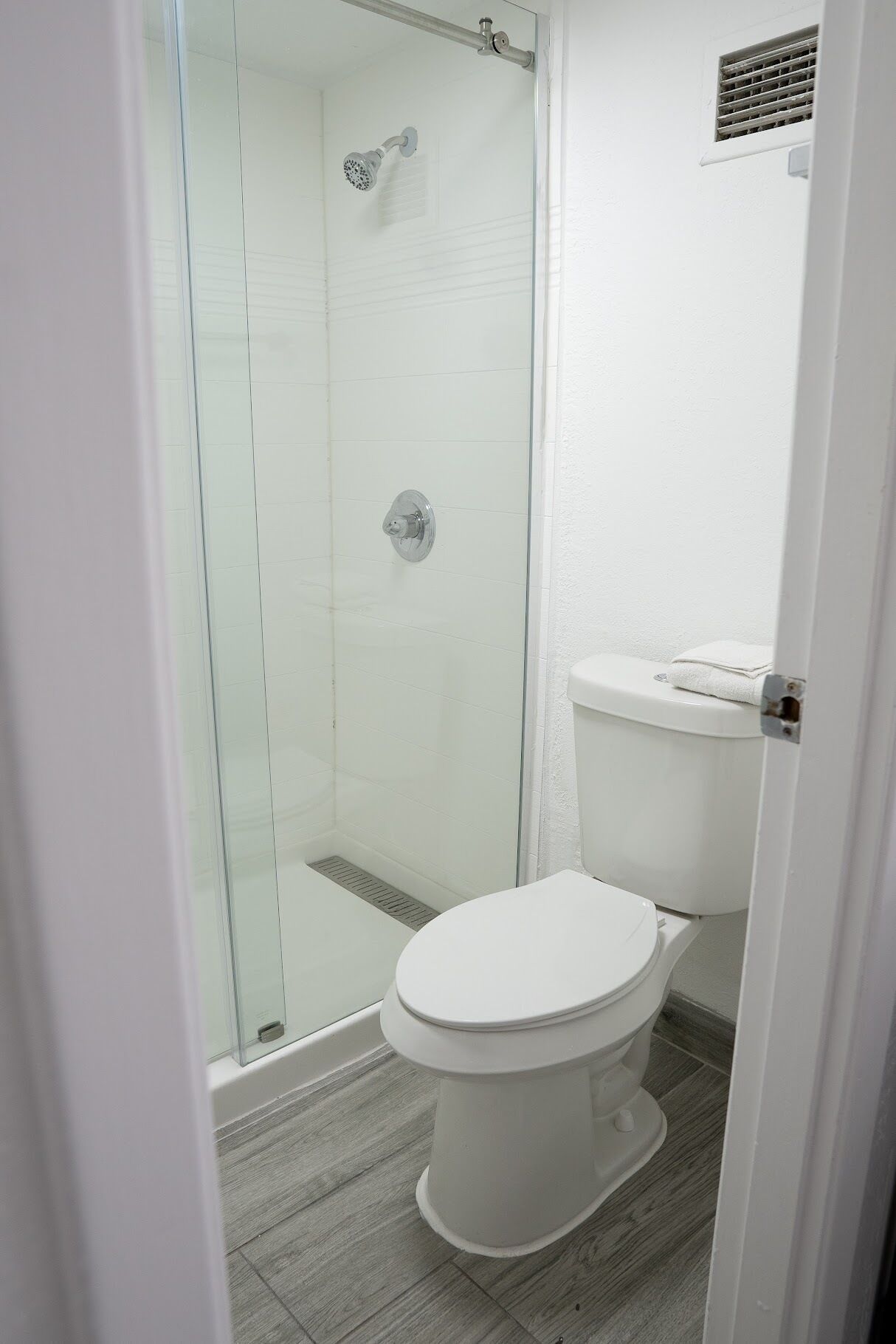 A modern bathroom with a glass-enclosed shower, a white toilet, and a small sink.