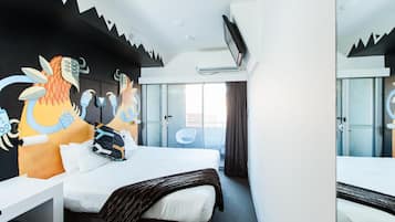 A hotel room with a bed, a desk, a chair, a TV, and a window with curtains.