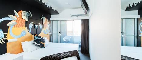 Quarto de hotel com cama, escrivaninha, cadeira, televisão e janela com cortinas.