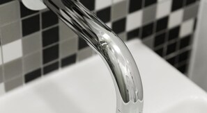 A close-up of a chrome faucet with water flowing from it. - Majestic Minima Hotel (North Adelaide)