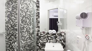 A modern bathroom with a glass-enclosed shower, a white sink, and a hairdryer on the wall. - Majestic Minima Hotel (North Adelaide)