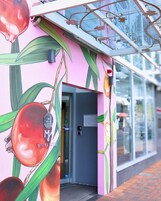 Fachada de edificio con un vibrante mural de granadas y hojas.