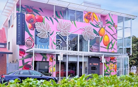 A building with a vibrant fruit mural, a glass facade, and a sign for 'MINIMA HOTEL'.
