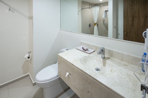Une salle de bain comprenant des toilettes, un lavabo avec un miroir et un espace douche.