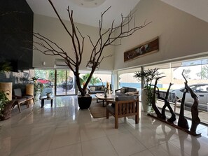 A spacious living area with a large tree, a sofa, a coffee table, and a dining table.
