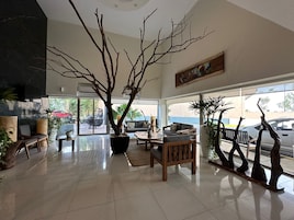 Un salón espacioso con un gran árbol, un sofá, una mesa de centro y una mesa de comedor.