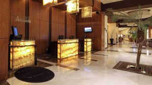 A reception area with wooden paneling, reception desks, a television, and a palm tree.