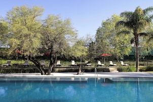 Área de piscina com espreguiçadeiras e piscina azul cristalina.