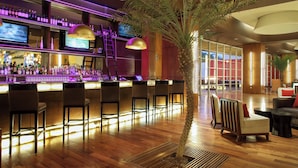 A bar area with multiple seating options, a television, and a large plant.