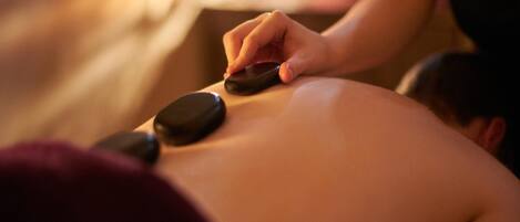 A person receiving a back massage with stones.