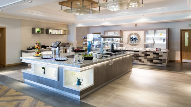 Une cuisine moderne dotée d’un îlot central, d’appareils électroménagers intégrés et d’un revêtement mural décoratif.