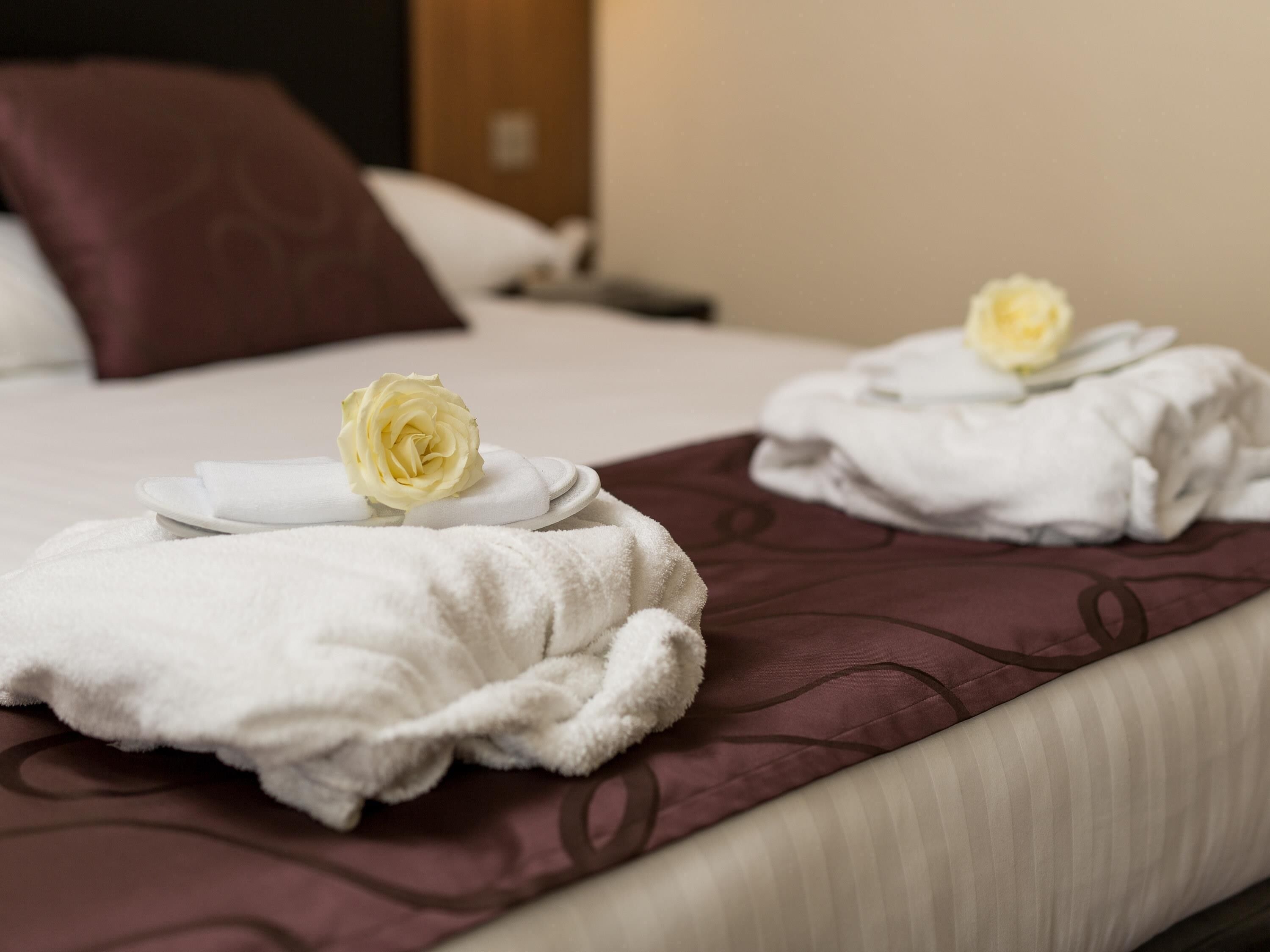 Ein Hotelzimmer mit einem Bett, Kissen und Handtüchern, jedes verziert mit einer Rose.