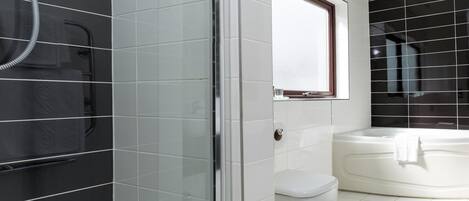 Un baño moderno con cabina de ducha de vidrio, inodoro blanco y bañera.