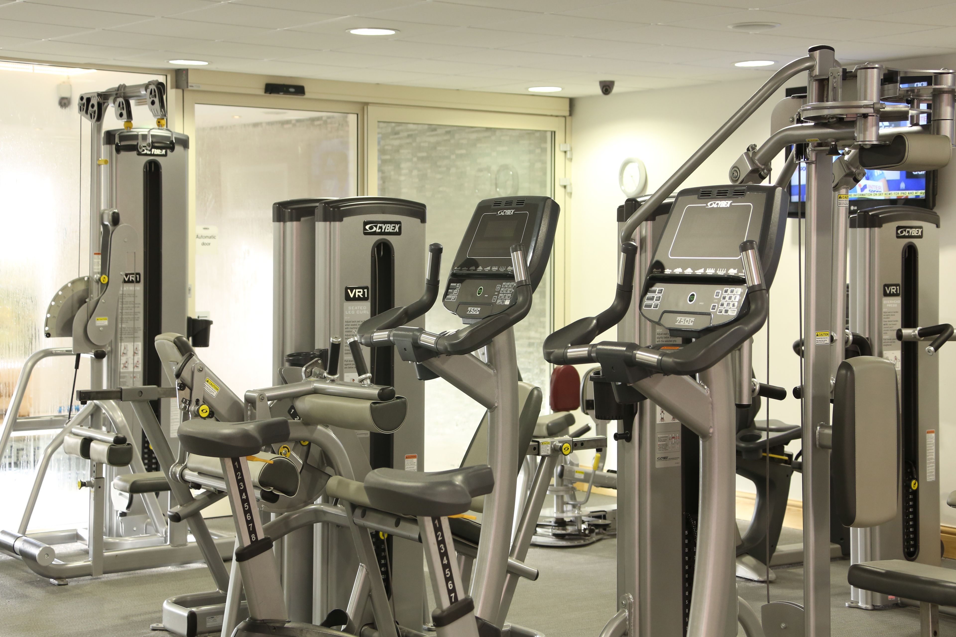 A gym with various exercise machines including treadmills, a stationary bike, and weight machines.