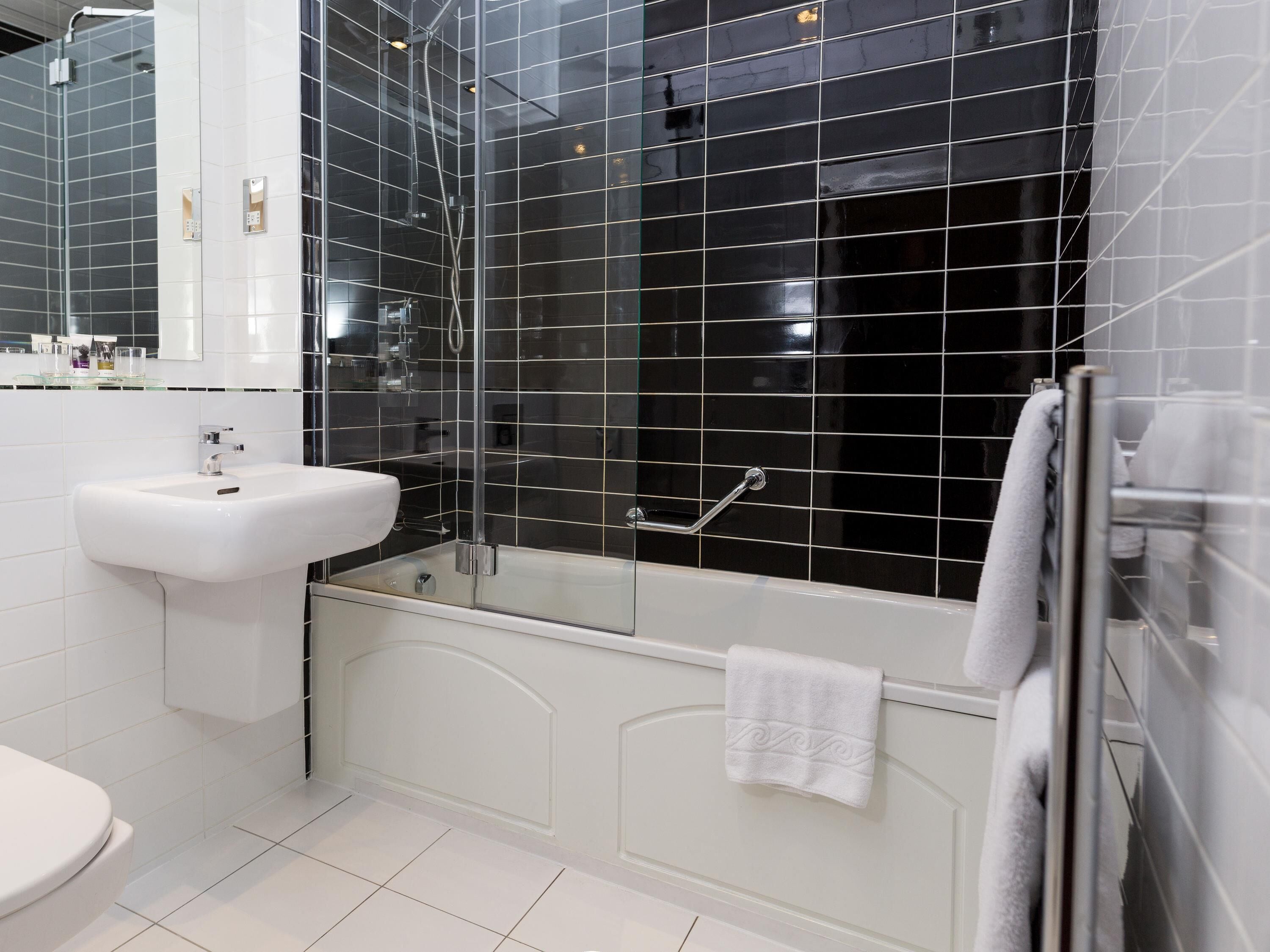 A modern bathroom with a glass-enclosed shower, a white sink, and a bathtub.