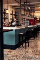 A bar area with a long counter, multiple taps, and a selection of bottles.