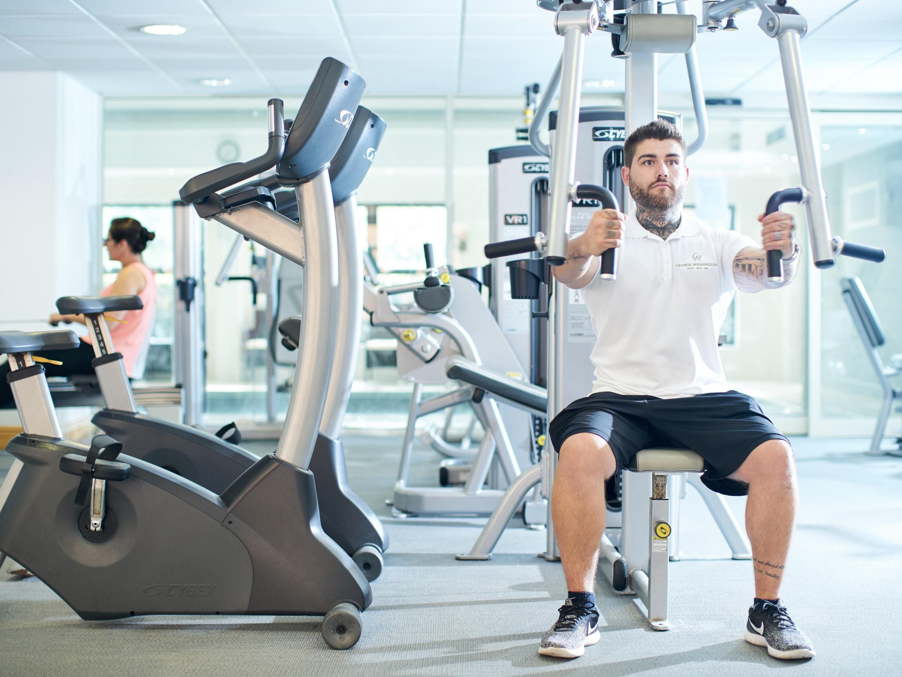 Een fitnessruimte met trainingsapparatuur, waaronder een roeiapparaat en een hometrainer.