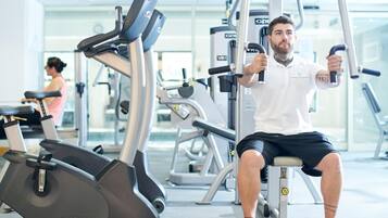 Un gimnasio con equipo de ejercicio, incluyendo una máquina de remo sentado y una bicicleta estática.