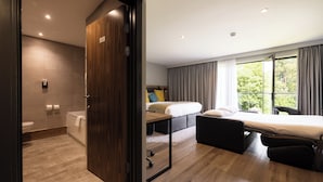 Une chambre d’hôtel moderne avec un plancher en bois, un lit, un bureau et une vue sur l’extérieur.