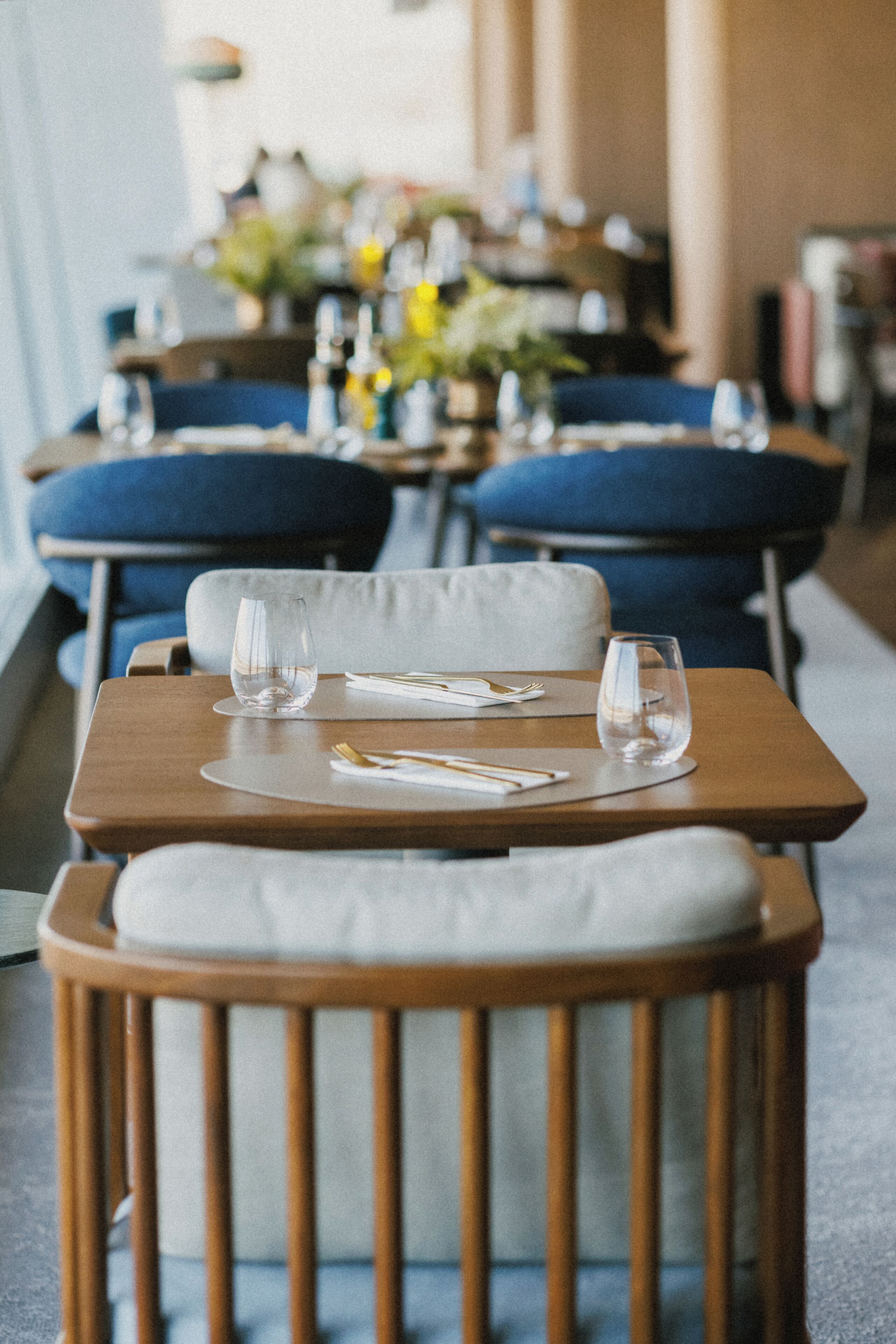 Comedor con mesas dispuestas para dos, con mesas de madera y sillas acolchadas.