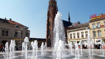 A public square with a central fountain and a historic church in the background.