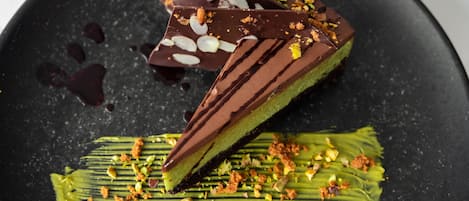 Un postre con chocolate y elementos verdes sobre un plato negro.