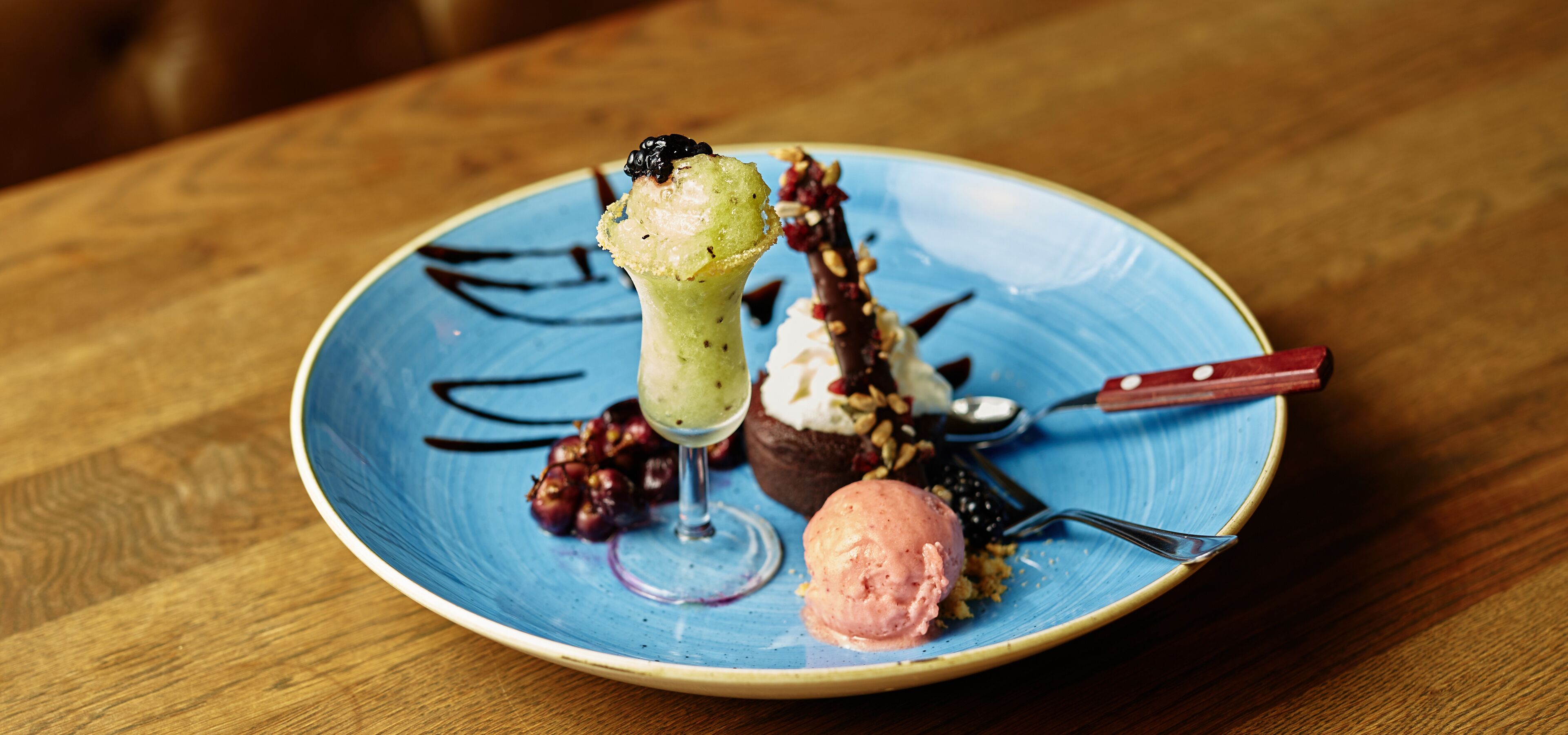 Un plato de postres con diferentes opciones, incluyendo una bola de helado, un postre de chocolate y un postre verde en un vaso.