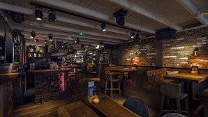 Eine gemütliche Bar mit Holzkuben, einer Ziegelwand und verschiedenen Lampen.