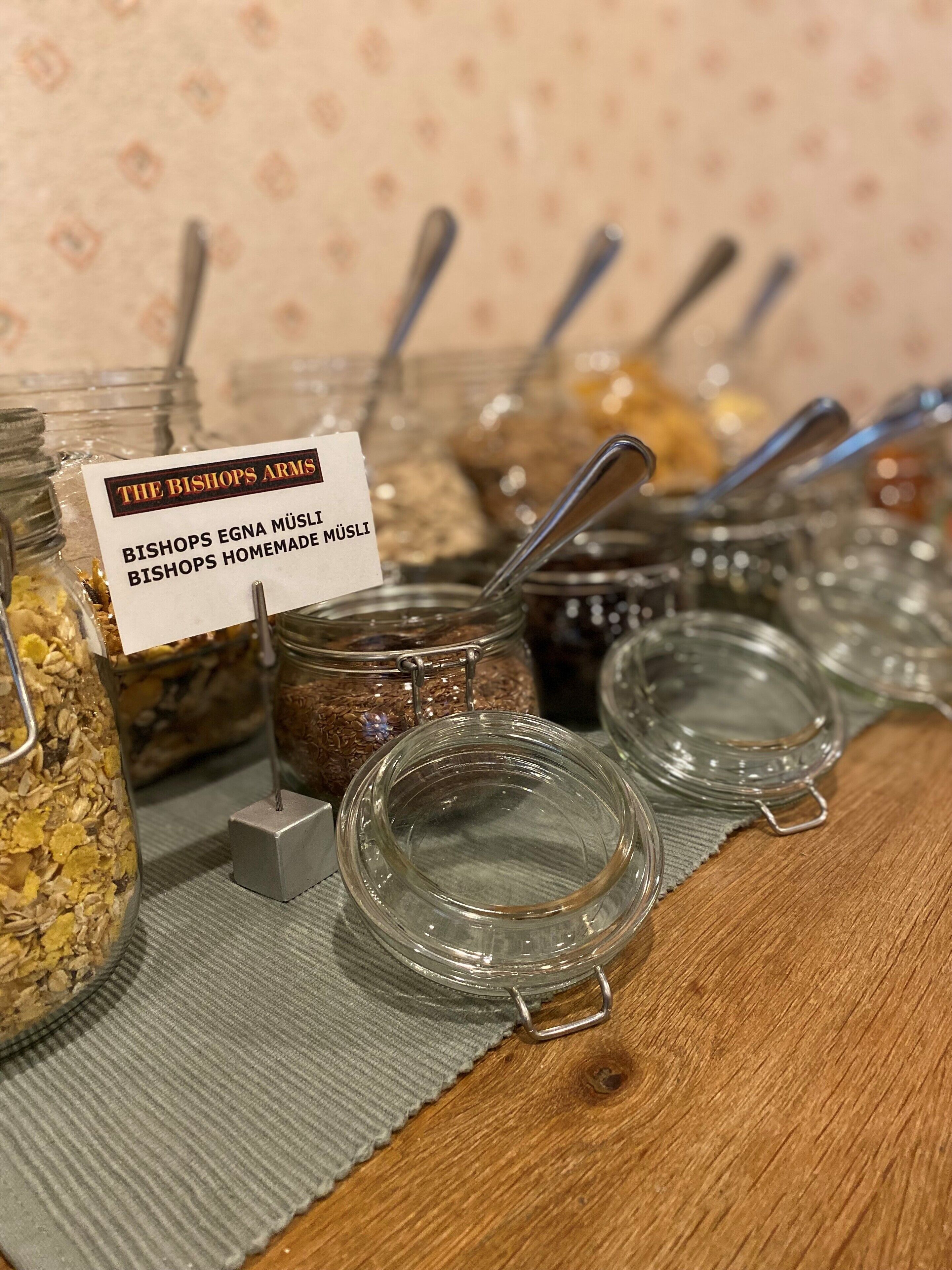 A display of homemade muesli jars with labels, arranged on a wooden surface.