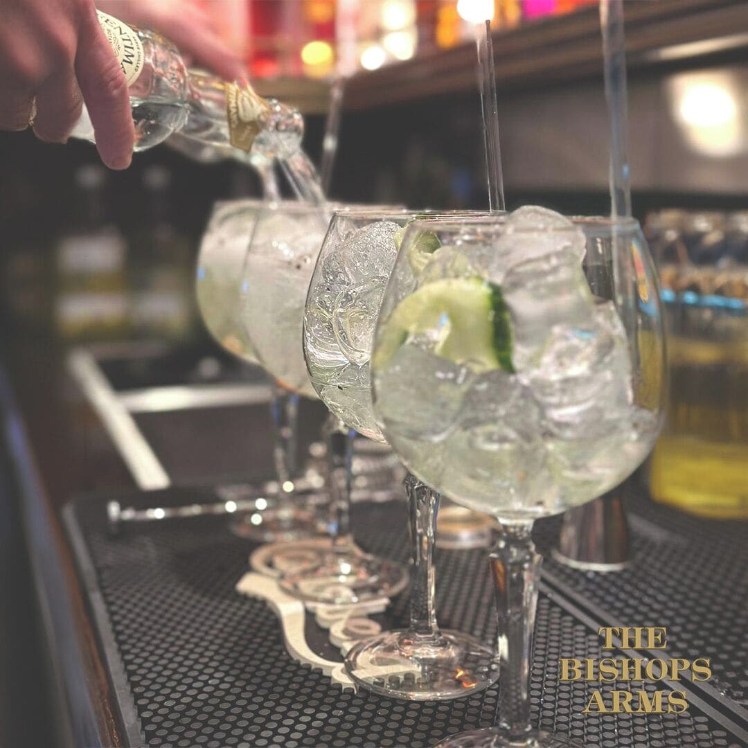 A bar setting with glasses of a clear beverage, ice cubes, and lime slices.