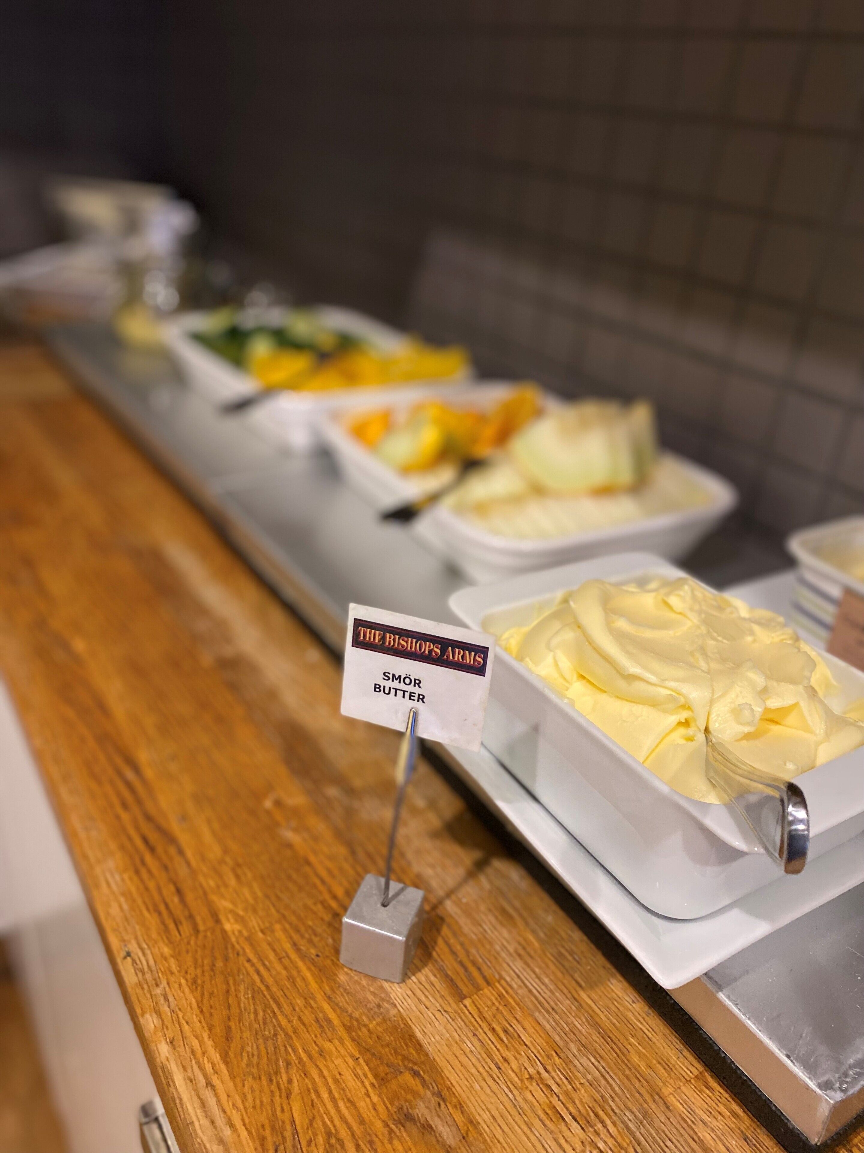 Un bufé con diversos alimentos, incluyendo un cartel que dice 'The Bishops Arms Smör Butter'.