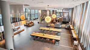 A spacious, modern lounge area with multiple seating arrangements, including tables and sofas, and large windows providing natural light. - Comfort Hotel Union Brygge - Drammen (Drammen)