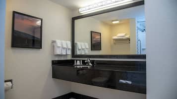 Un baño moderno con un lavabo negro, un espejo grande y toallas blancas.