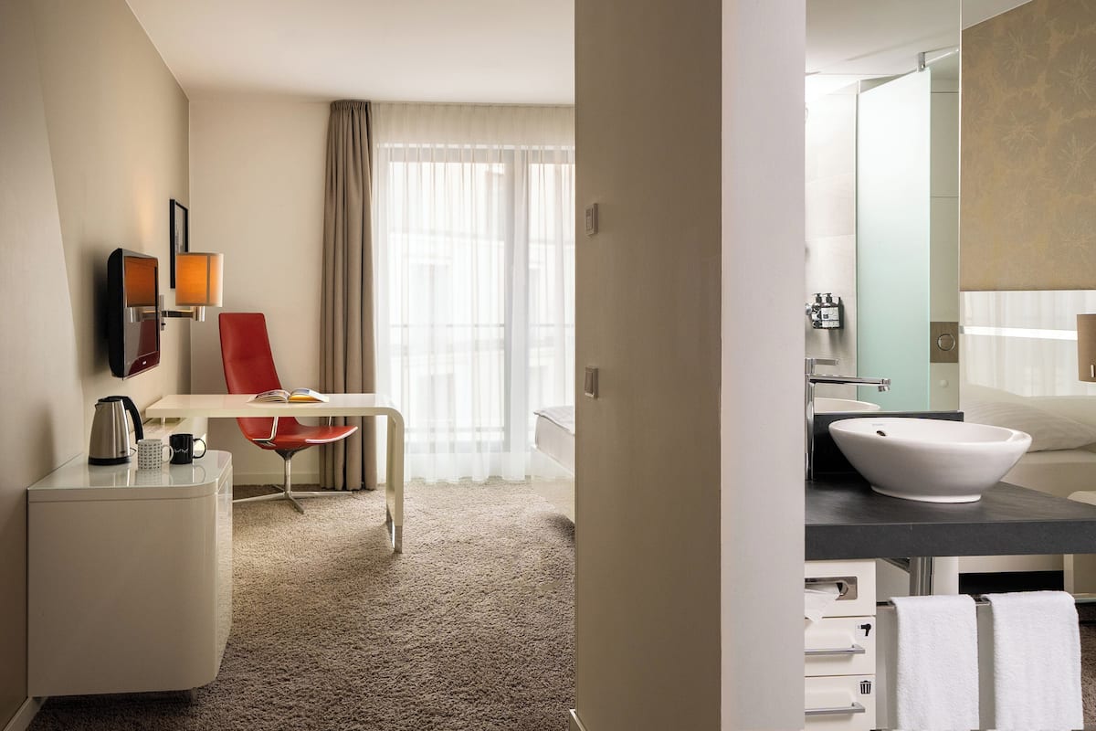 Une chambre d’hôtel équipée d’un bureau, d’une chaise et d’un grand miroir.