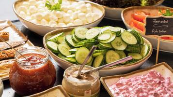 A buffet with various food options including sliced cucumbers, cheese balls, and a fish salad sign.