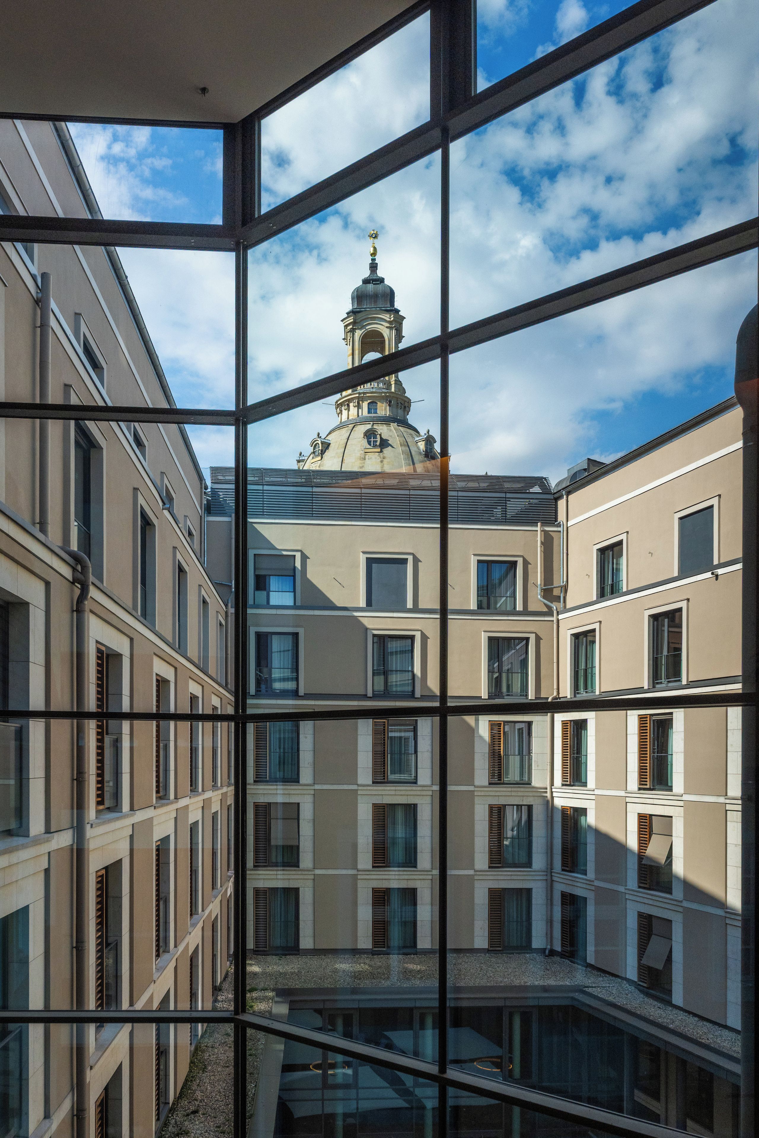 Blick durch ein Fenster auf ein Gebäude mit Innenhof, im Hintergrund eine Kuppelstruktur.