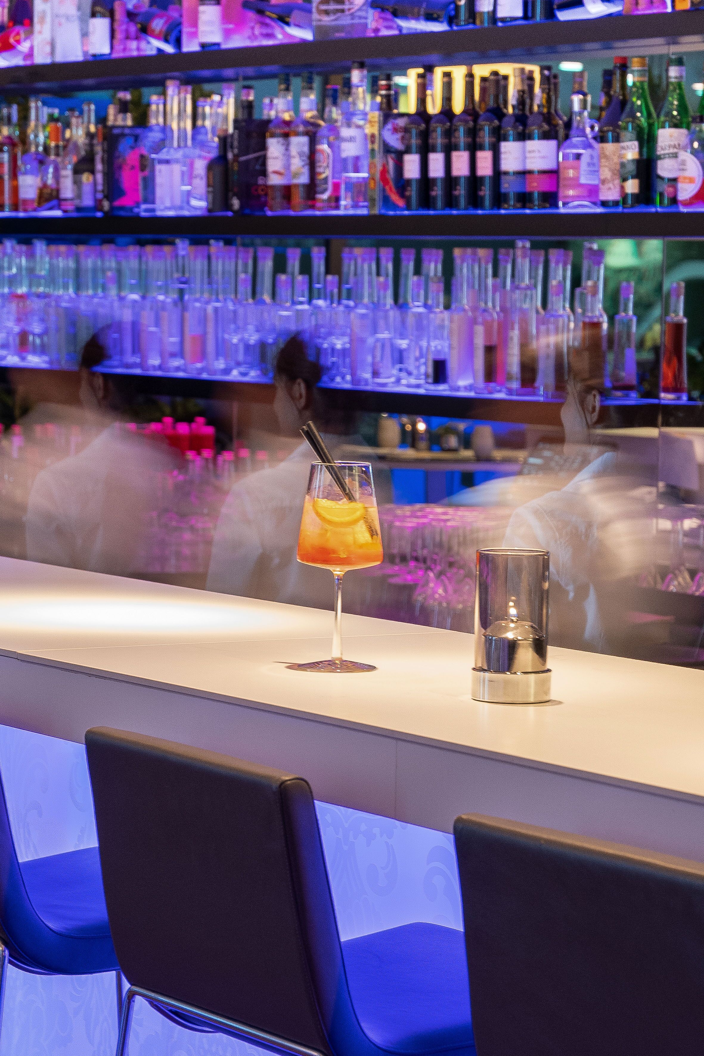 Een bar met een cocktailglas en een kaars op het aanrecht.