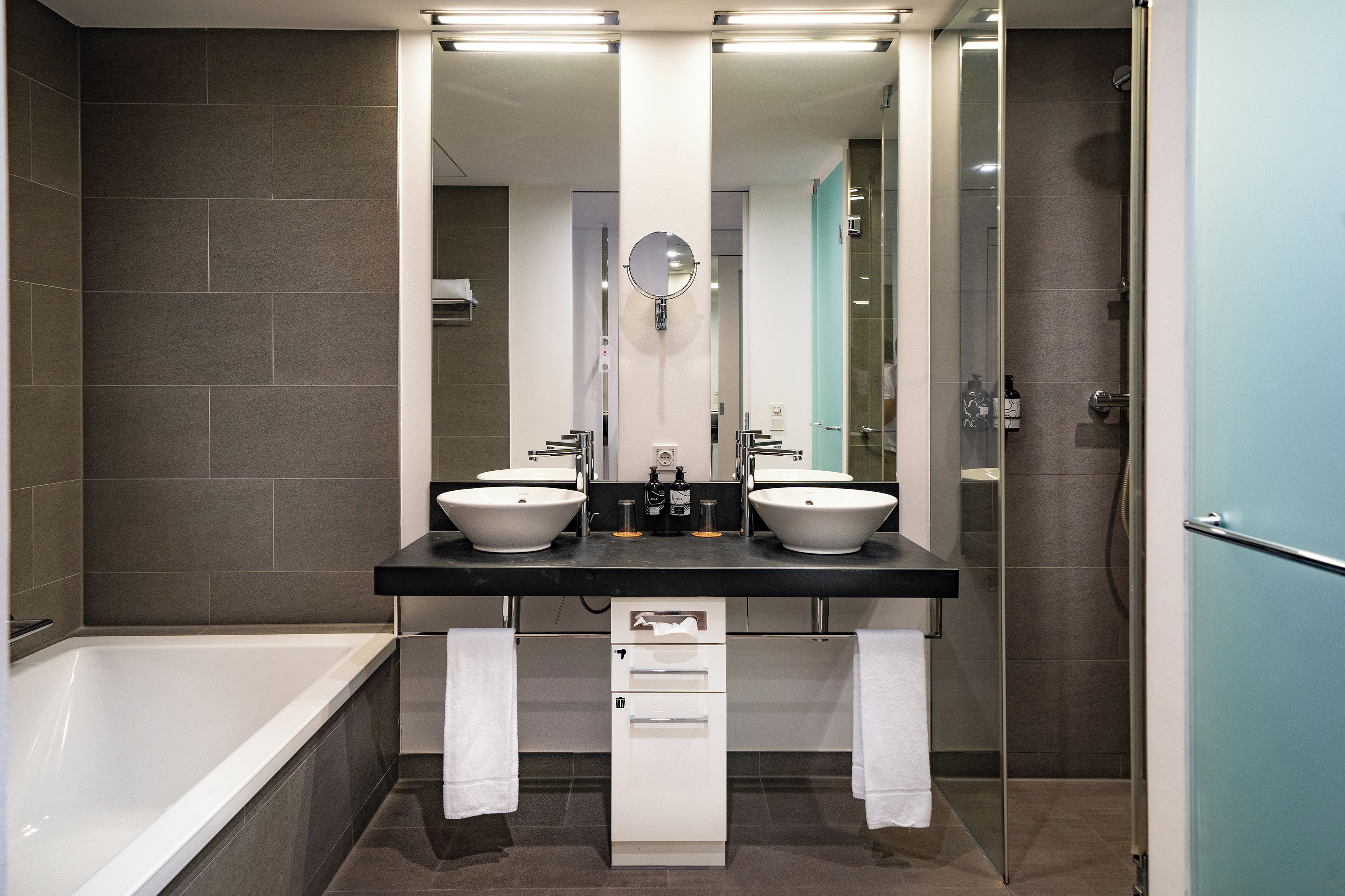 Un baño moderno con dos lavamanos, un espejo y una bañera.