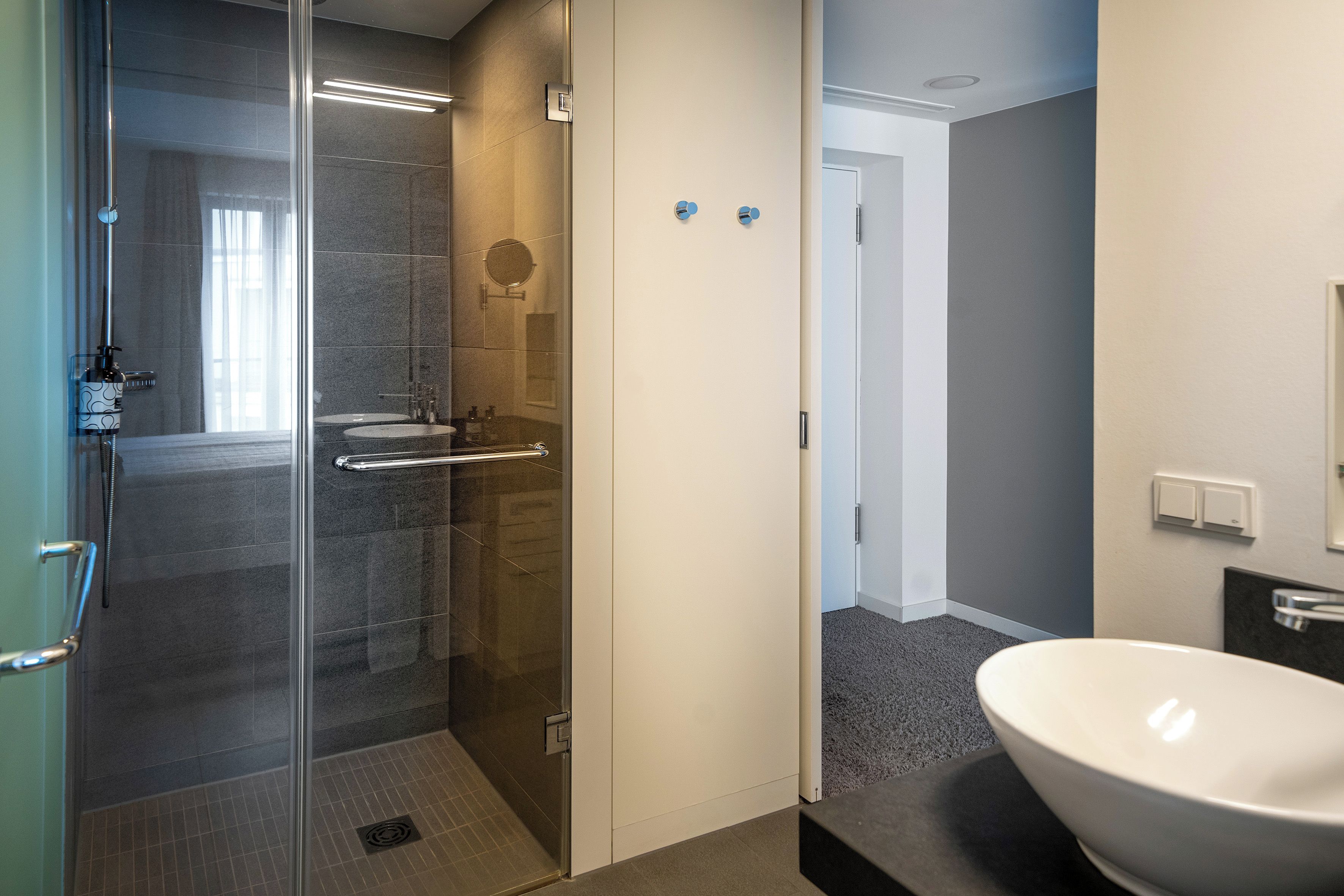 A modern bathroom with a glass-enclosed shower, a white sink, and a mirror.