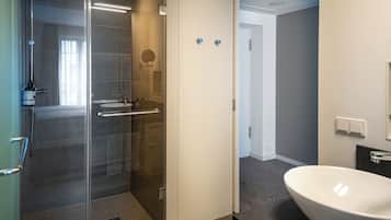 A modern bathroom with a glass-enclosed shower, a white sink, and a mirror.