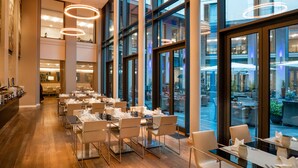 Eine moderne Hotellobby mit einer langen Rezeption, mehreren Sitzbereichen und großen Fenstern mit Blick auf die Stadt.