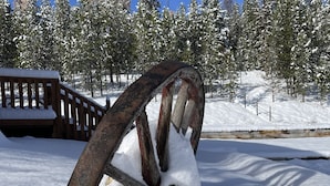 A snow-covered wooden structure with a metal wheel in a snowy landscape.