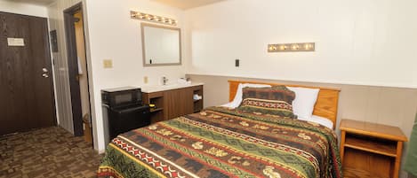 Un dormitorio con una cama grande, una mesita de noche de madera, un aparador y un espejo con luces.