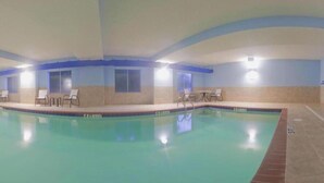 Una piscina interior con sillas de descanso y suelo de baldosas.