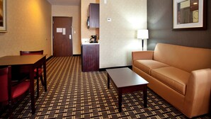 A hotel room with a dining table, a sofa, a coffee machine, and a lamp. - Holiday Inn Express Hotel & Suites AMITE by IHG (Amite)