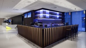 A modern bar area with a sleek, dark counter and illuminated shelves.