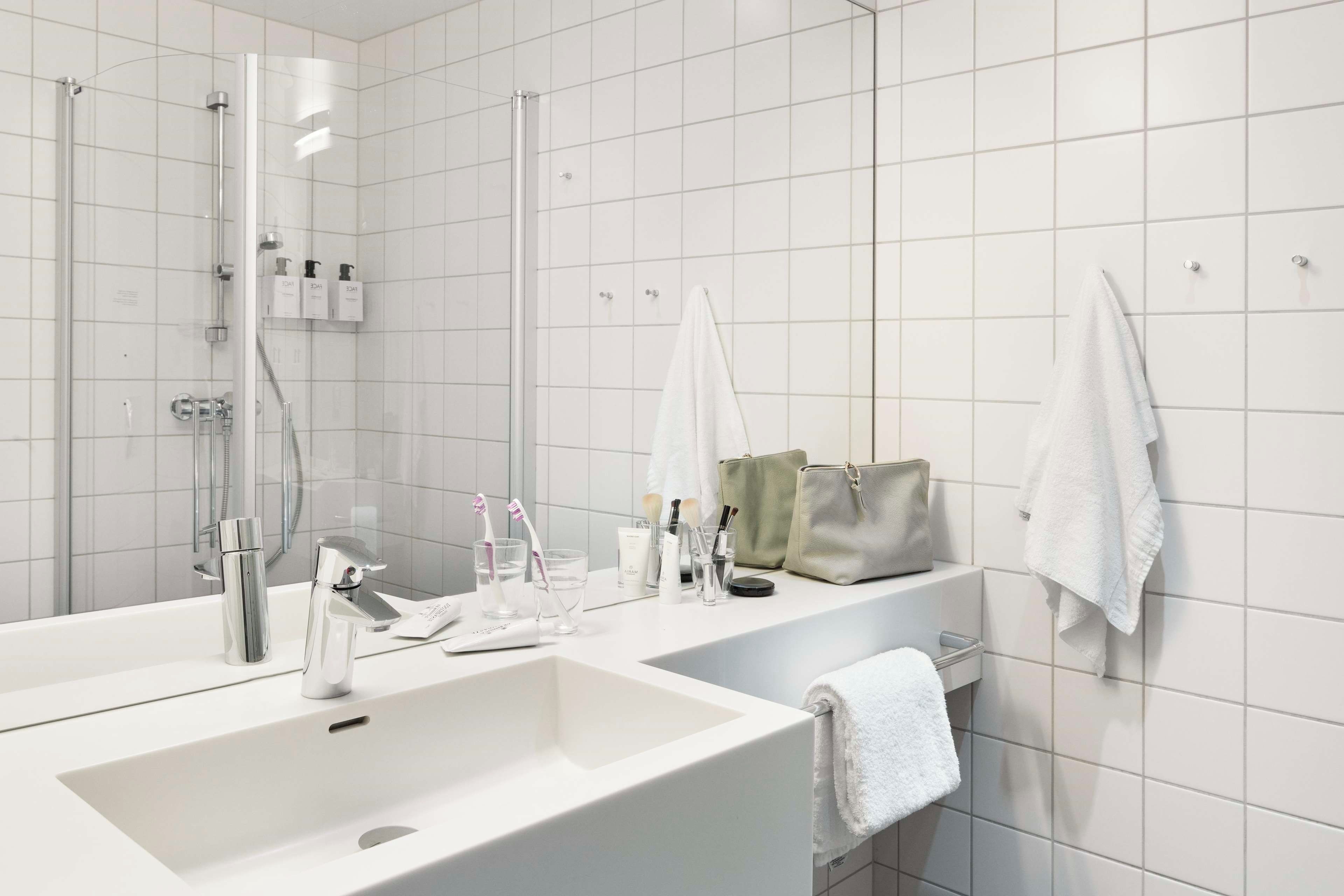 Ein modernes Badezimmer mit einem großen weißen Waschbecken, einer Duschkabine aus Glas und einem Handtuchhalter mit mehreren Handtüchern.